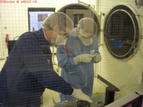 Giles and Wouter mount our baby in the Thermo Vac chamber, one end of which is in the clean room. Duncan makes a few last minute software changes, while Graham rests his hand on the oven door